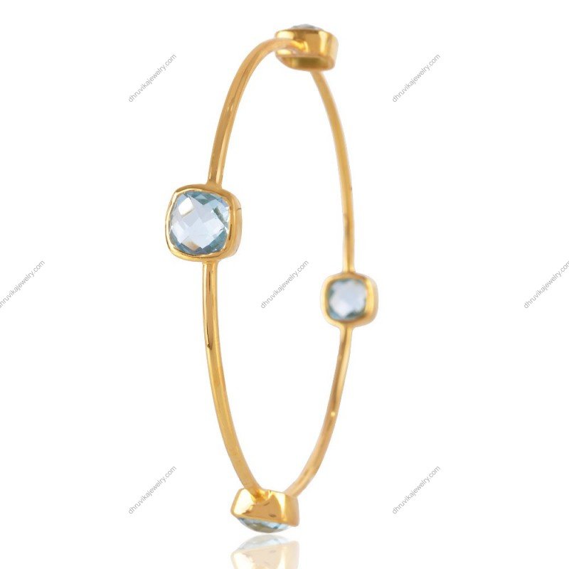 Gold-plated blue topaz bangle with faceted gemstones, handcrafted for a sophisticated style.